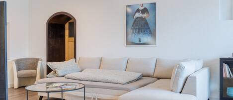 Una sala de estar con sofá, sillón, mesa de centro y un cuadro en la pared.
