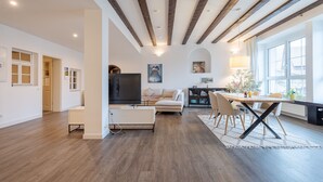 Un salón amplio con una televisión de pantalla plana, un sofá y una zona de comedor con mesa y sillas.