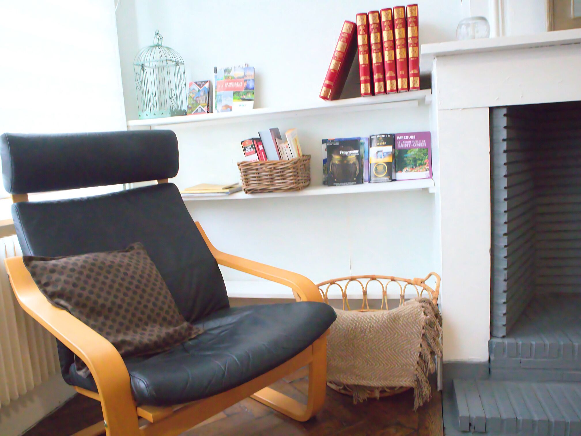 Una habitación con una silla de madera, una chimenea y una estantería con libros y objetos decorativos.