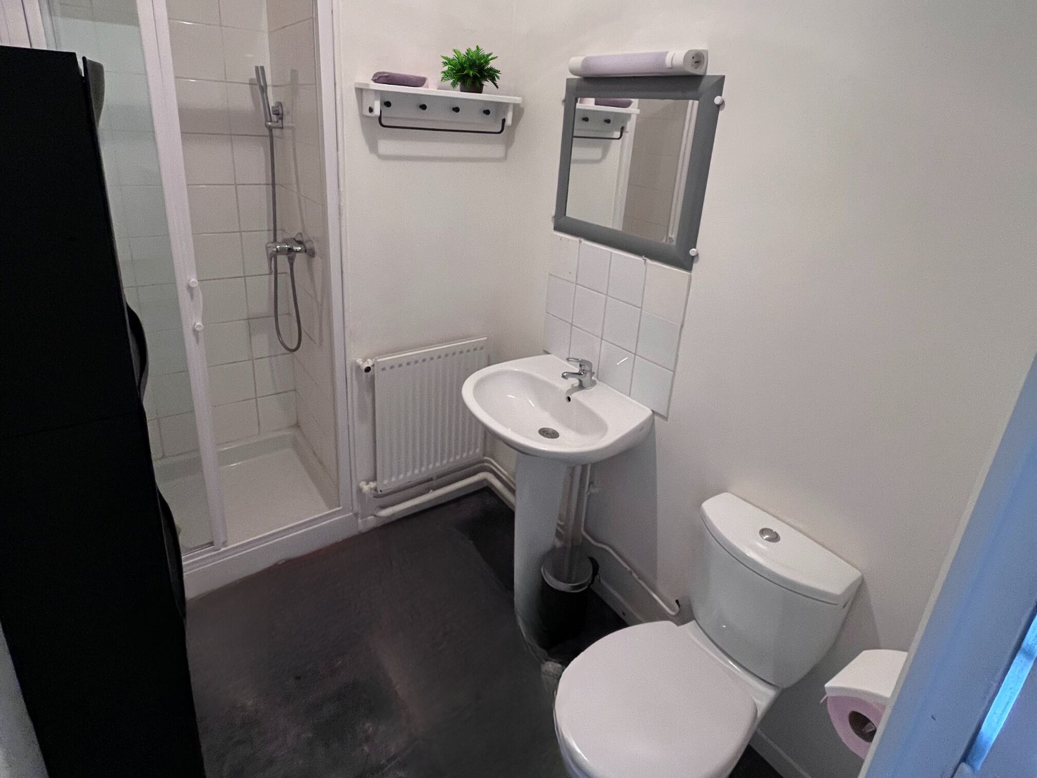 A small bathroom with a toilet, sink, and shower.