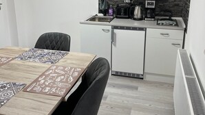 Een praktische keuken met witte kastjes, een magnetron, een koffiezetapparaat en een kleine koelkast.