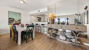 A modern kitchen with a dining area, a large mirror, and a view of the beach. - Cozy Ocean View Family Retreat - 3BR - Amelia by the Sea (Fernandina Beach)