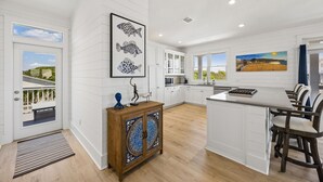 Une cuisine moderne avec des meubles blancs, un îlot central et un coin repas avec des chaises.