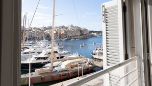 A view of a marina with multiple boats docked, a cityscape in the background, and a balcony railing. - Bormla Seafront 3 Bedroom Apartment (Birgu)