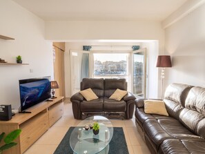 A living room with a sofa, a TV, and a coffee table. - Bormla Seafront 3 Bedroom Apartment (Birgu)