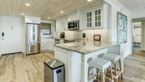 Una cocina moderna con armarios blancos, electrodomésticos de acero inoxidable y encimera de mármol.