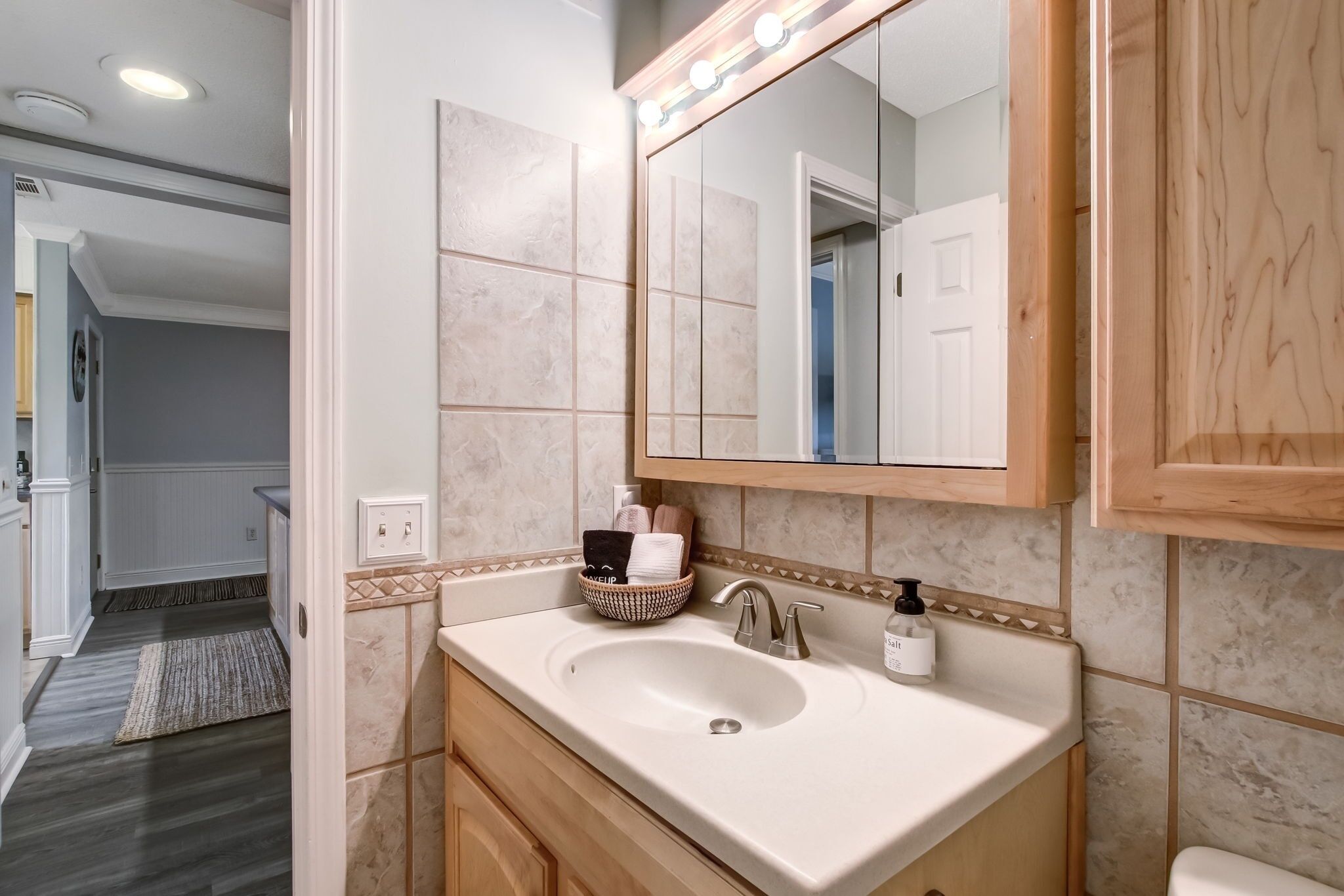 Un baño con un espejo grande, un lavabo y un armario de madera.