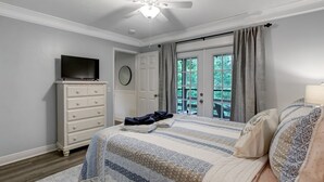 A bedroom with a bed, a dresser, a television, a ceiling fan, and a window with curtains. - Fernandina Beach Hidden Gem Amelia Landings - 9F (Fernandina Beach)