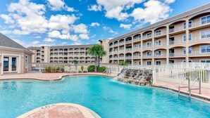 A hotel with a swimming pool, a waterfall feature, and multiple balconies. - Top Floor Beach View Condo Ocean Park 409 (Fernandina Beach)