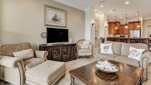 A spacious living room with a large flat-screen TV, a wooden cabinet, and a beige sofa. - Haven across the Ocean - Pet Friendly 1931 S Fletcher (Fernandina Beach)