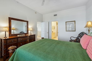 A bedroom with a large bed, a dresser, a mirror, and two doors leading to other rooms. - Sunshine Bliss at Fernandina Beach Ocean View, Pool, Hot Tub (Fernandina Beach)