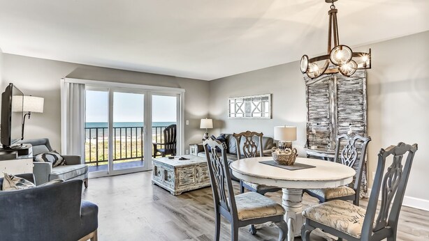 A spacious living room with a dining area, large windows with a view, and a chandelier. - Freshly Renovated 2BR Dream Condo Beachfront Stunning Views (Fernandina Beach)