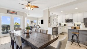 A spacious kitchen with white cabinets, a large island, and a dining area with a wooden table and chairs. - Luxury Private Beachfront Condo w/ Parking Garage & Stunning Views (Fernandina Beach)