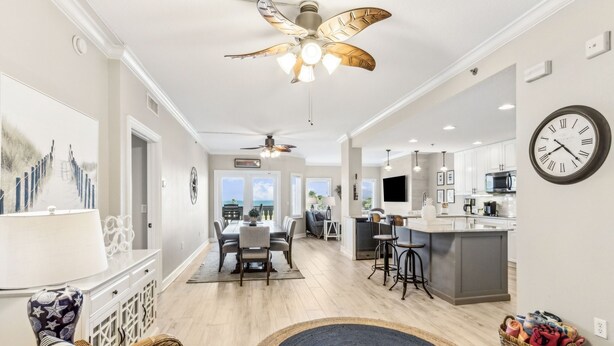 A spacious living area with a dining table, wicker furniture, and a kitchen with a bar area. - Luxury Private Beachfront Condo w/ Parking Garage & Stunning Views (Fernandina Beach)