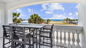 A balcony with a view of the beach, featuring a table and chairs. - Luxury Private Beachfront Condo w/ Parking Garage & Stunning Views (Fernandina Beach)