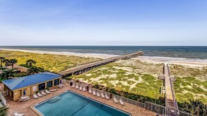 A beachside resort with a swimming pool, lounge chairs, and a pier extending into the ocean. - Beachfront Family Condo w/ Pool, Fishing, and Pier Access Amelia by the Sea (Fernandina Beach)