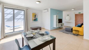 Un salon moderne comprenant un coin repas, un téléviseur et un canapé.