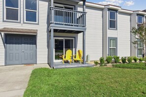 A two-story residential building with a front porch, a garage, and a small landscaped area with yellow chairs. - Tranquil Beach Retreat Fernandina Shores 6398 (Fernandina Beach)