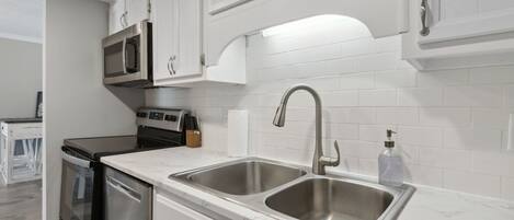A modern kitchen with white cabinets, stainless steel appliances, and a double sink.