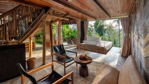 Un espace intérieur spacieux avec un escalier en bois, un canapé en osier et une table à manger.