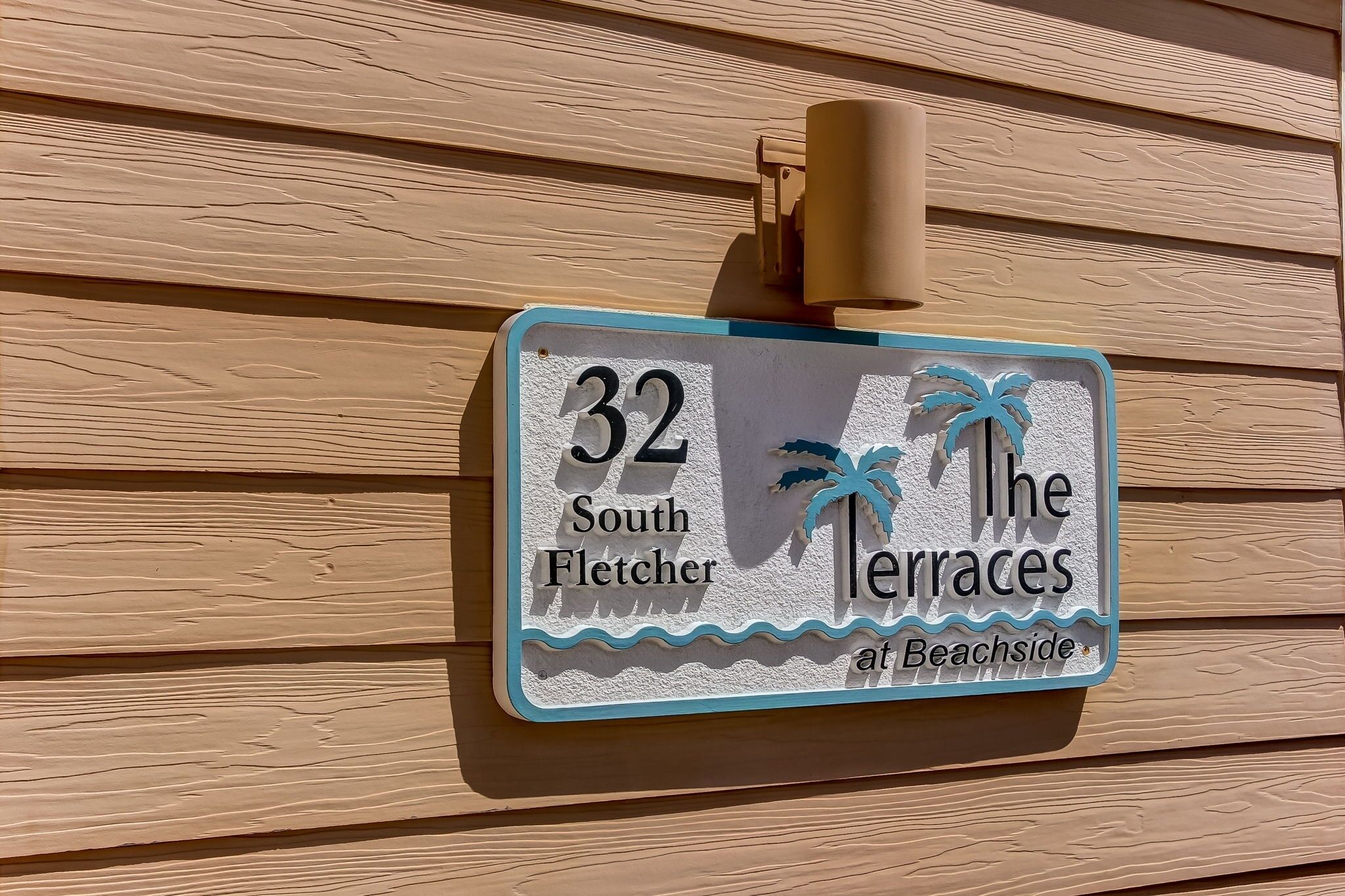 A house number sign for '32 South Fletcher at Beachside' with palm tree decorations.