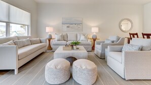 Un salón moderno con un sofá beige, dos sillones, una mesita de centro y una mesita auxiliar con una lámpara.