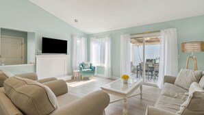 A living room with beige sofas, a white coffee table, and a teal armchair. - North End Gem - Pet Friendly Fernandina Beach Cottage (Fernandina Beach)