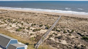A beach with a long wooden boardwalk leading to the shore, sandy dunes, and a clear view of the ocean. - Charming Family Retreat w/ Ocean View Sandpiper Loop - 95076 (Fernandina Beach)