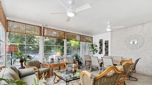 A spacious living area with wicker furniture, large windows, and ceiling fans. - Newly Renovated 2BR by the Beach Amelia Island (Fernandina Beach)