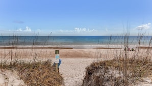 A beach with a clear sky, a sandy path leading to the water, and a signpost. - Newly Renovated 2BR by the Beach Amelia Island (Fernandina Beach)