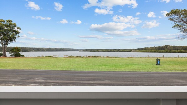 A grassy area with a lake and trees in the background.