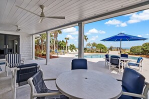 A covered outdoor patio with a pool, lounge chairs, and umbrellas. - Beachfront Luxury Home w/ Private Pool (Fernandina Beach)