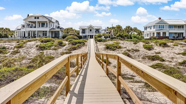 A wooden boardwalk leading to beachfront properties with multiple stories and balconies. - Beachfront Luxury Home w/ Private Pool (Fernandina Beach)