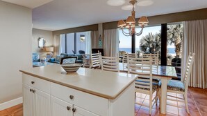A spacious living area with a large window, a dining table with chairs, and a kitchen island. - Pet Friendly 2 Bedroom Villa w/ Pool - Captain's Court (Fernandina Beach)