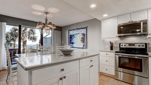 A modern kitchen with white cabinetry, a central island, a built-in oven, and a microwave. - Pet Friendly 2 Bedroom Villa w/ Pool - Captain's Court (Fernandina Beach)
