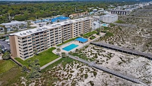 A multi-story hotel with a pool, surrounded by greenery and a beach. - Ground Floor Beachfront Condo Amelia by the Sea (Fernandina Beach)