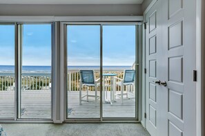 A room with a sliding glass door leading to a deck with a view of the ocean and beach. - Spacious Beachfront 3BR in Amelia Island Sandpiper Loop (Fernandina Beach)