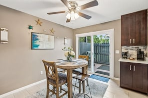 A kitchen with a round dining table, wooden chairs, a ceiling fan, and a view to the backyard. - Pet Friendly Beach Retreat Fernandina Shores - 6355 (Fernandina Beach)