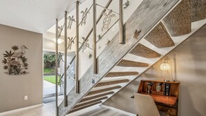 Eine moderne Treppe mit Holzvertäfelung und Metallgeländern, die zu einem Raum mit Schreibtisch und Stuhl führt.