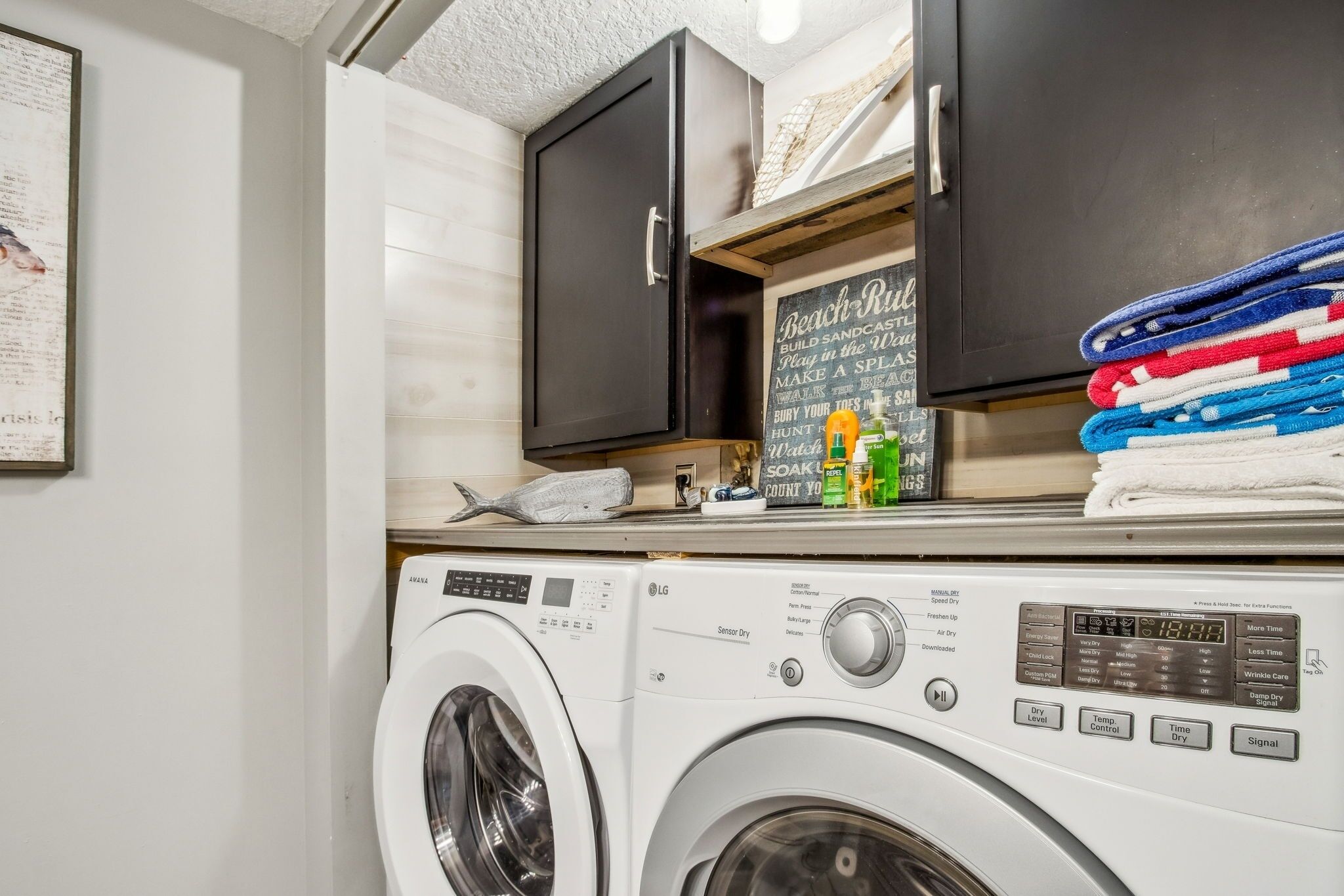A laundry area with a washing machine and dryer, a chalkboard with laundry tips, and neatly stacked towels.