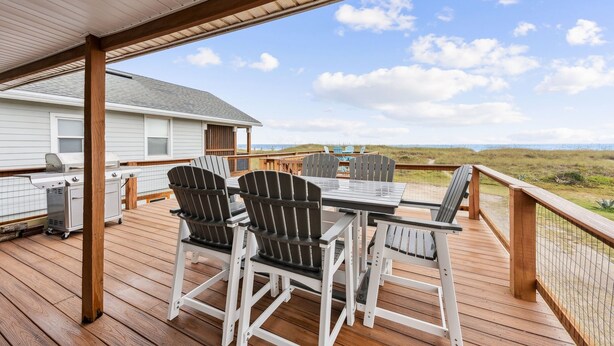 A covered outdoor deck with a table and chairs, a grill, and a view of the beach. - Spacious Beachfront Duplex - Top Floor - Dog Friendly 124 S Fletcher (Fernandina Beach)