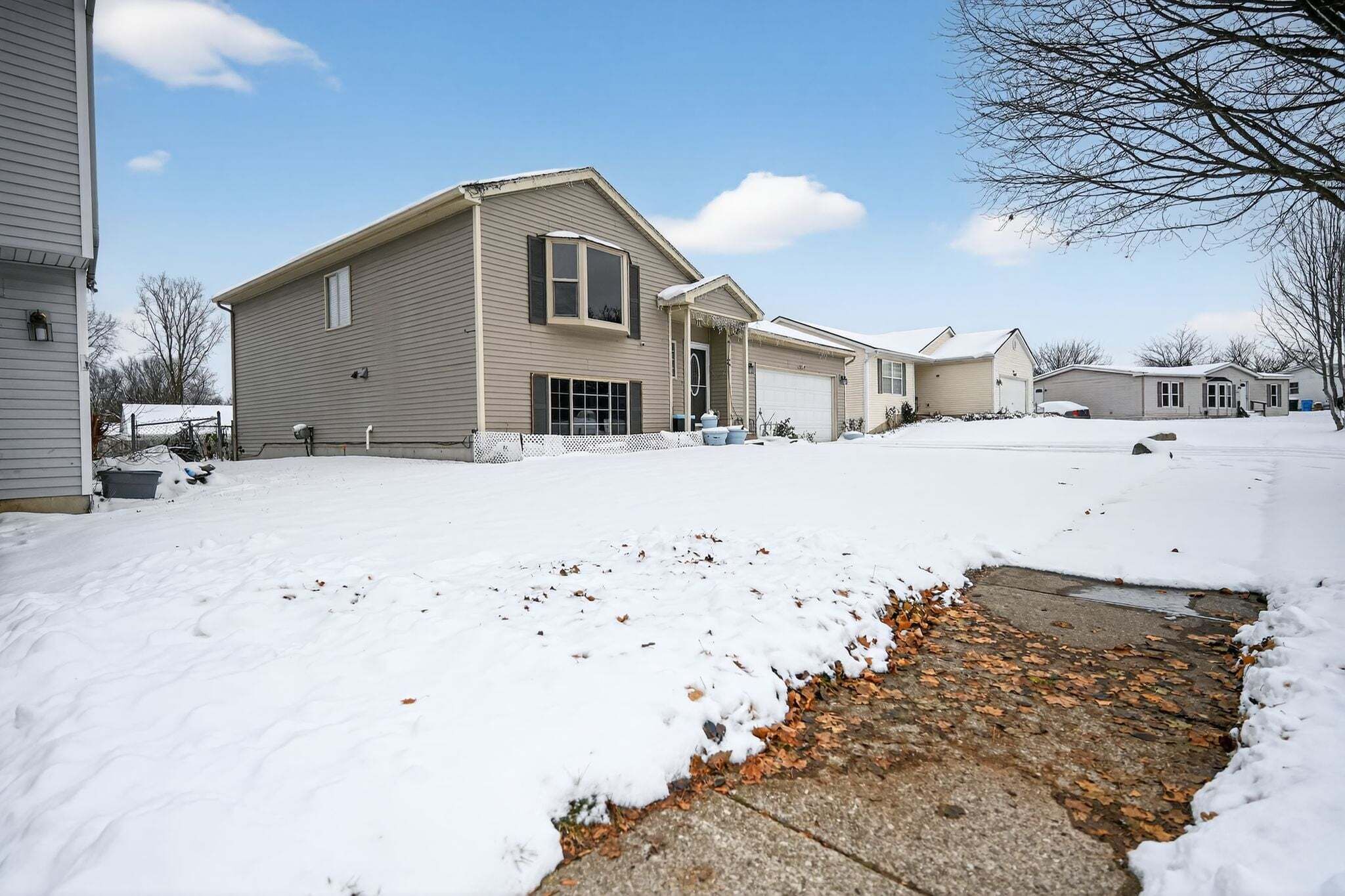 A residential area with houses, a driveway, and a snow-covered ground.