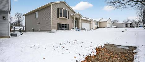 A residential area with houses, a driveway, and a snow-covered ground.