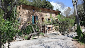 A stone building with a rustic appearance, surrounded by trees and a gravel driveway. - Domaine Saint Amour – Gîte Au Lac: 2-Hectare Estate with Lake, Waterfall & Pool (Trans-en-Provence)