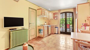 A kitchen with a TV, a radiator, cabinets, and a window with a view. - Domaine Saint Amour – La Cascade Cottage, 2 ha Estate with Lake, Waterfall & Pool (Trans-en-Provence)
