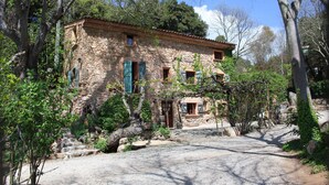 A stone building with a rustic appearance, surrounded by trees and a gravel driveway. - Domaine Saint Amour – La Cascade Cottage, 2 ha Estate with Lake, Waterfall & Pool (Trans-en-Provence)