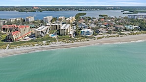 A coastal resort area with multiple buildings, including hotels and residential properties, adjacent to a sandy beach and a large body of water. - 'bout Time 2 Bedroom Condo (Siesta Key)