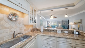 A modern kitchen with granite countertops, white cabinetry, and a built-in island. - 'bout Time 2 Bedroom Condo (Siesta Key)