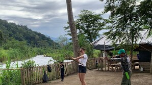 A person practicing archery in an outdoor setting with a river and forest in the background. - Eden travel Cabecars (Valle La Estrella)