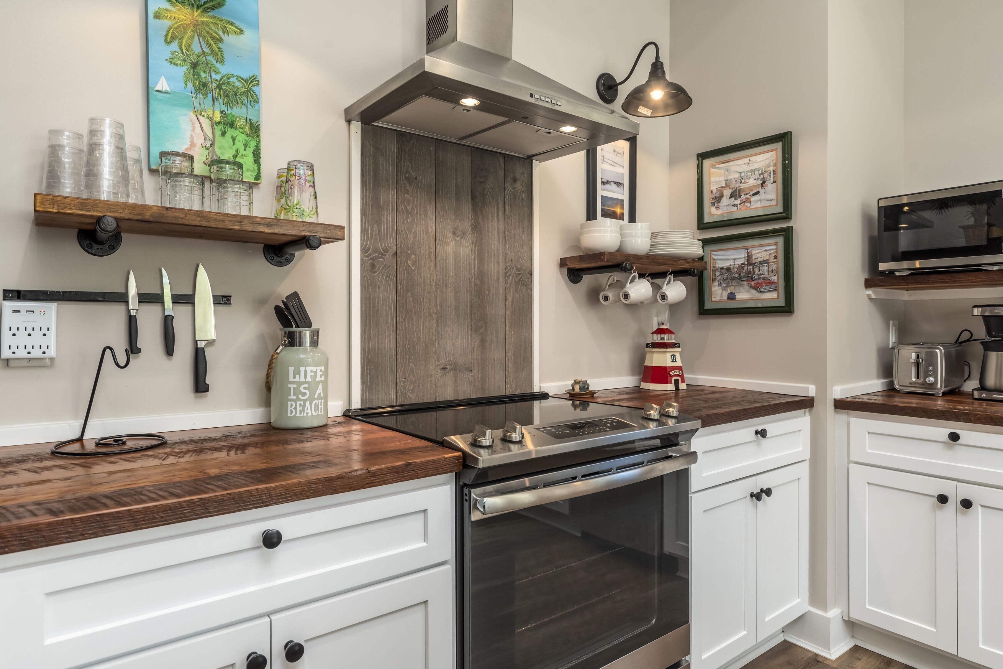 A kitchen with a stainless steel range hood, wooden countertops, white cabinets, and a built-in oven.